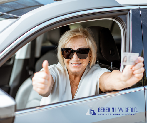 A woman holding her license in the drivers seat